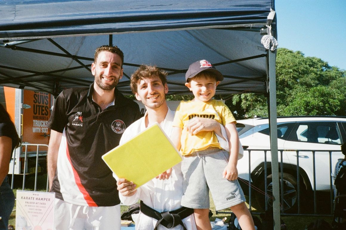 Sensei Richi and Sensei Yoni with a young MKK East student at a community event